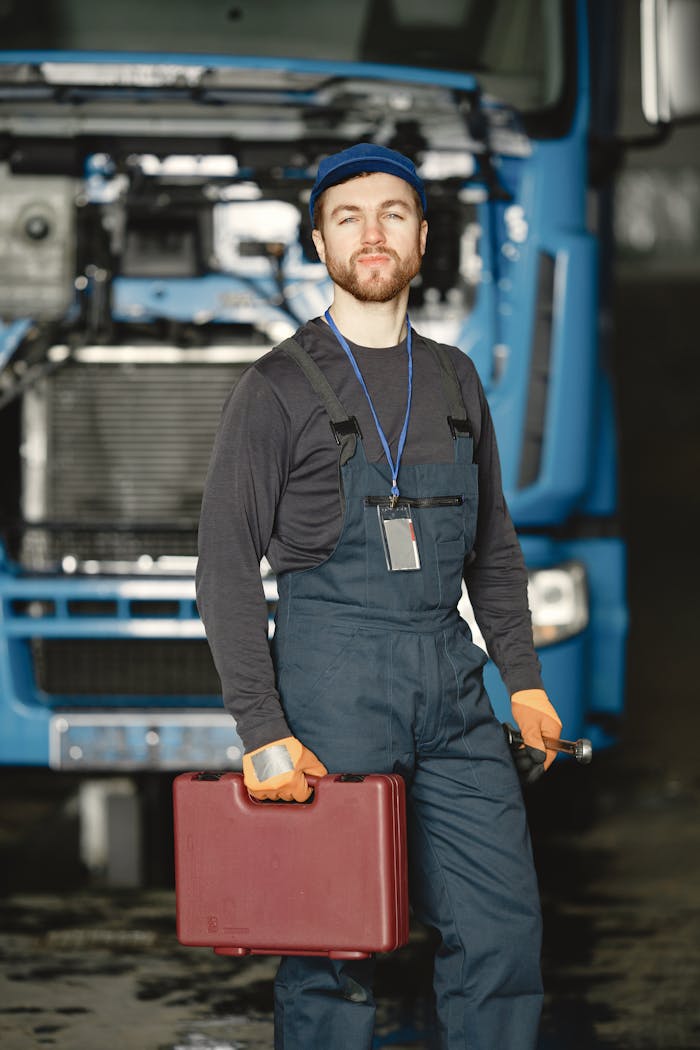 Auto mechanic with toolbox standing confidently in front of truck. Perfect for industrial and mechanical themes.